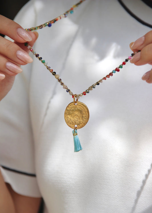 Collana lunga artigianale Laura Sciunnach con cristalli sfaccettati, ciondolo medaglia e nappina in tessuto – gioiello fatto a mano made in Italy.