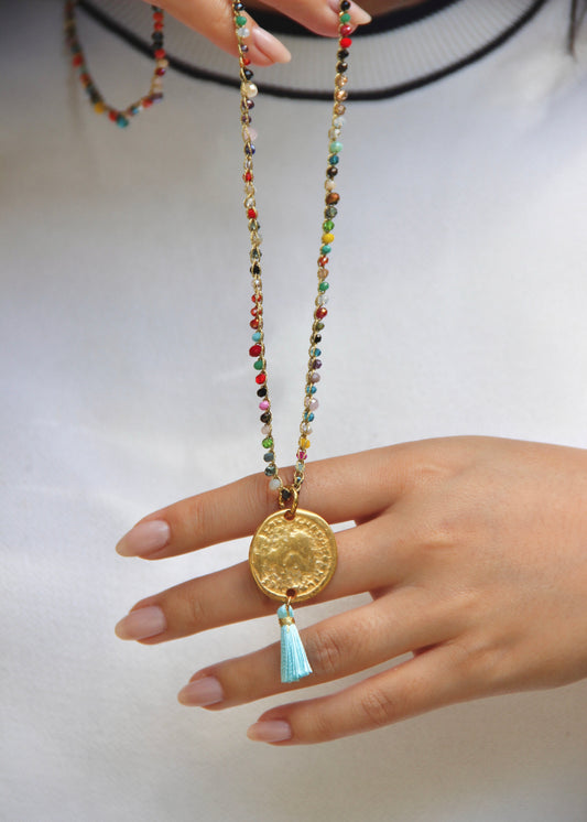 Collana lunga artigianale Laura Sciunnach con cristalli sfaccettati, ciondolo medaglia e nappina in tessuto – gioiello fatto a mano made in Italy.