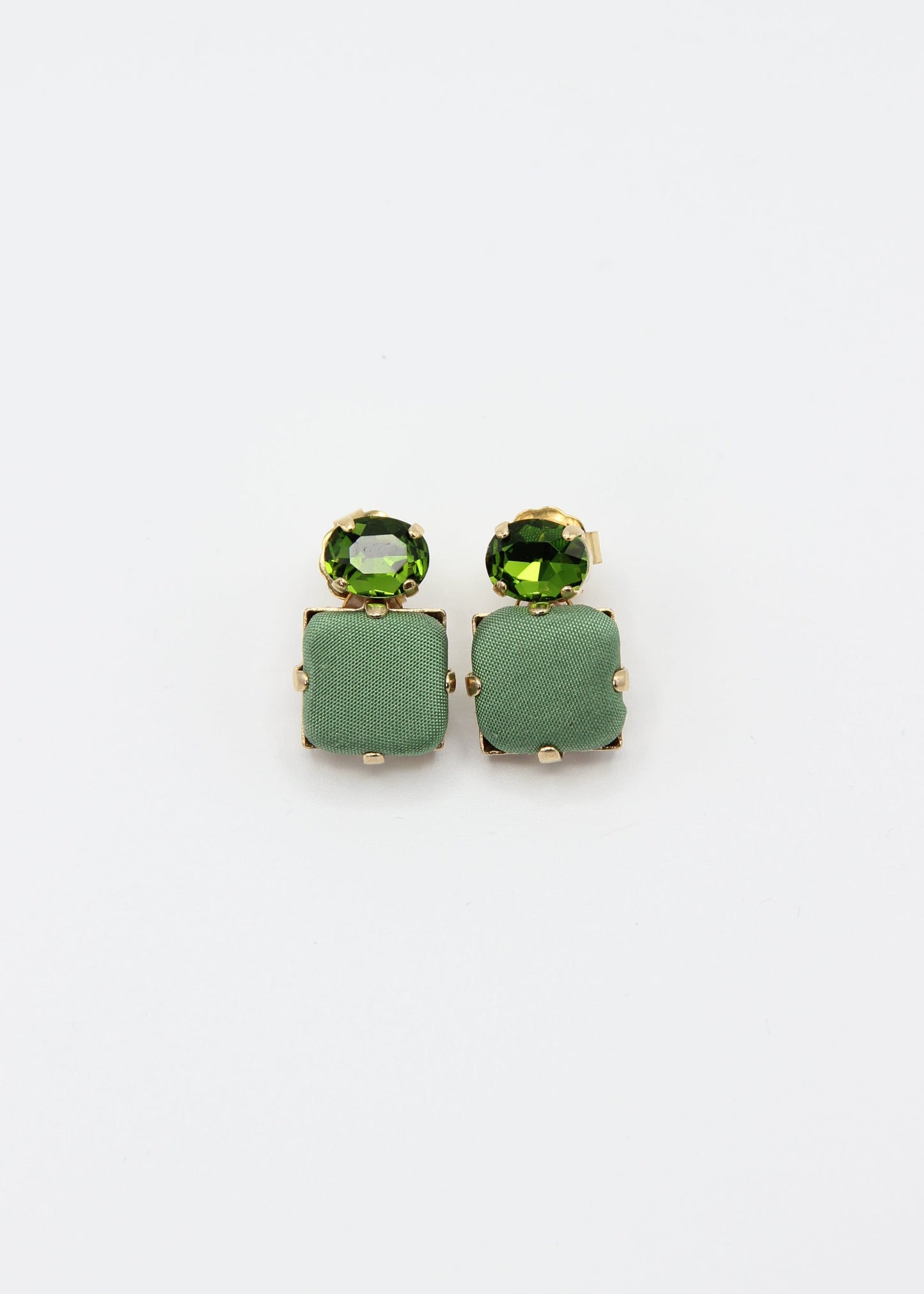 Orecchini verde salvia eleganti fatti a mano da Laura Sciunnach Bijoux, modello Metropolitan Siviglia con bottone quadrato in stoffa verde salvia e cristallo ovale verde tono su tono, design geometrico leggero e raffinato.