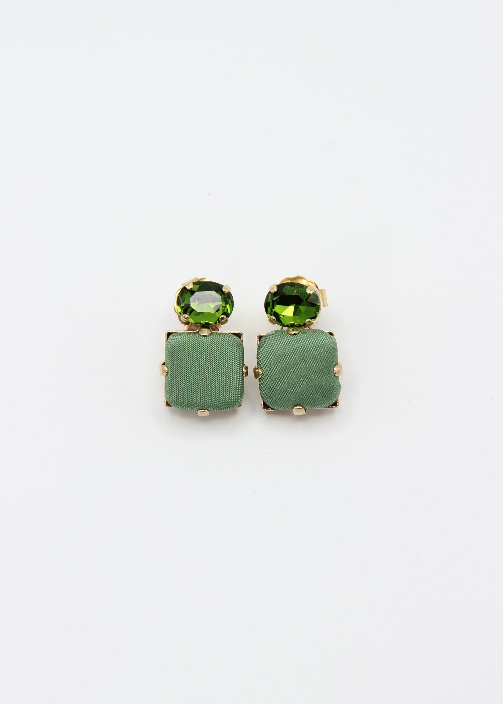 Orecchini verde salvia eleganti fatti a mano da Laura Sciunnach Bijoux, modello Metropolitan Siviglia con bottone quadrato in stoffa verde salvia e cristallo ovale verde tono su tono, design geometrico leggero e raffinato.