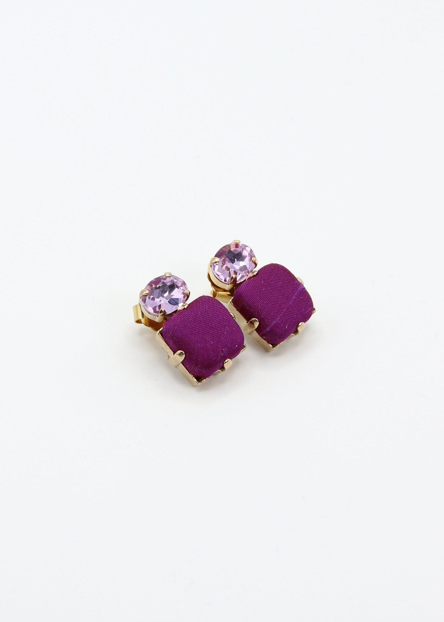 Orecchini viola eleganti fatti a mano da Laura Sciunnach Bijoux, modello Metropolitan Siviglia con bottone quadrato in stoffa viola e cristallo ovale lilla, design geometrico leggero e raffinato.