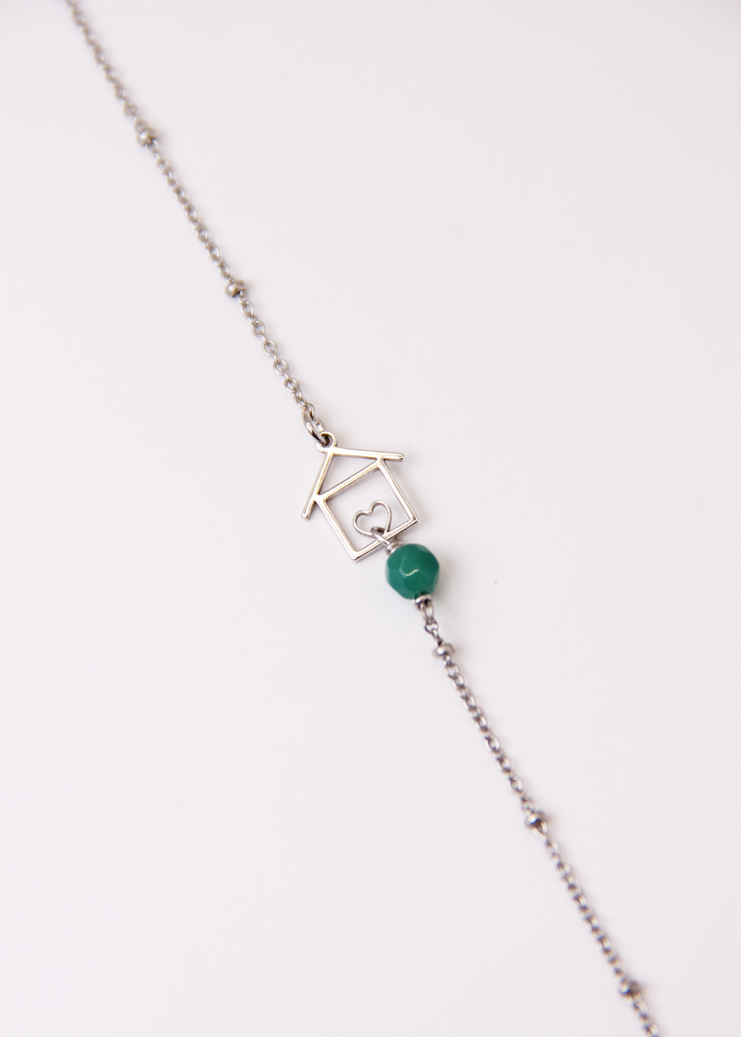Bracciale artigianale fatto a mano da Laura Sciunnach Bijoux in argento 925, con catena rosario e ciondolo a forma di casetta con pietra dura naturale. Disponibile in perla di lago, radice di rubino, agata nera e agata verde, e nelle varianti argento, argento placcato oro e oro rosa. Chiusura a moschettone, lunghezza regolabile
