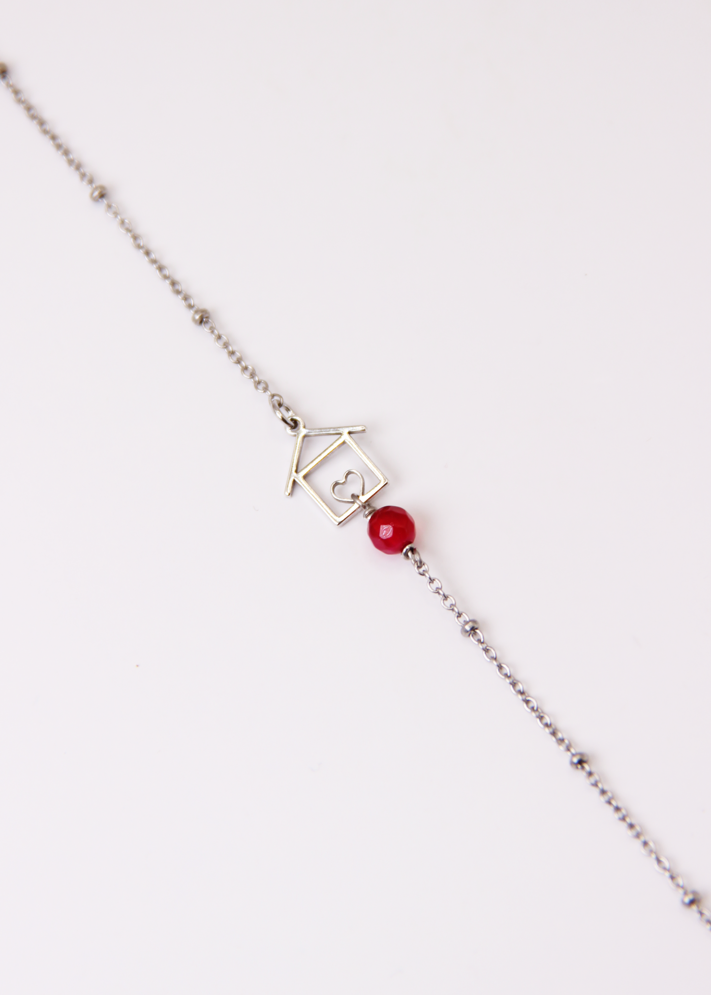 Bracciale artigianale fatto a mano da Laura Sciunnach Bijoux in argento 925, con catena rosario e ciondolo a forma di casetta con pietra dura naturale. Disponibile in perla di lago, radice di rubino, agata nera e agata verde, e nelle varianti argento, argento placcato oro e oro rosa. Chiusura a moschettone, lunghezza regolabile