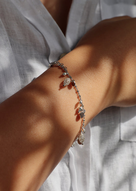 Bracciale Little Princess Monochrome Laura Sciunnach in argento 925 indossato al polso, con ciondoli traforati, medagliette e pepite. Gioiello artigianale Made in Italy dal design elegante e raffinato.