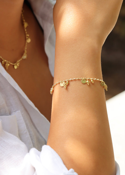 Bracciale Little Princess Monochrome Laura Sciunnach in argento 925 placcato oro giallo indossato al polso, con ciondoli traforati e dettagli luminosi. Bracciale artigianale donna Made in Italy.