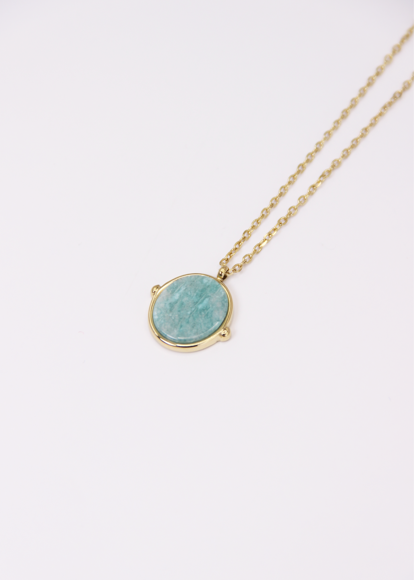 Collana in acciaio placcato oro con ciondolo ovale in pietra dura naturale e catena a maglia rettangolare fine. Disponibile in diversi colori, dal design elegante e senza tempo. Ogni pietra presenta variazioni naturali di colore e venature