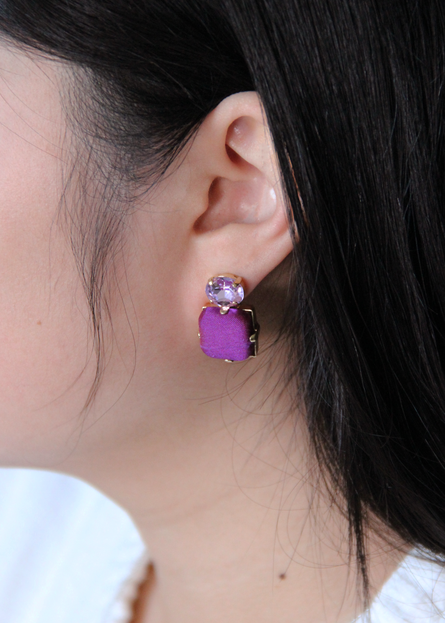 Orecchini viola eleganti fatti a mano da Laura Sciunnach Bijoux, modello Metropolitan Siviglia con bottone quadrato in stoffa viola e cristallo ovale lilla, design geometrico leggero e raffinato.