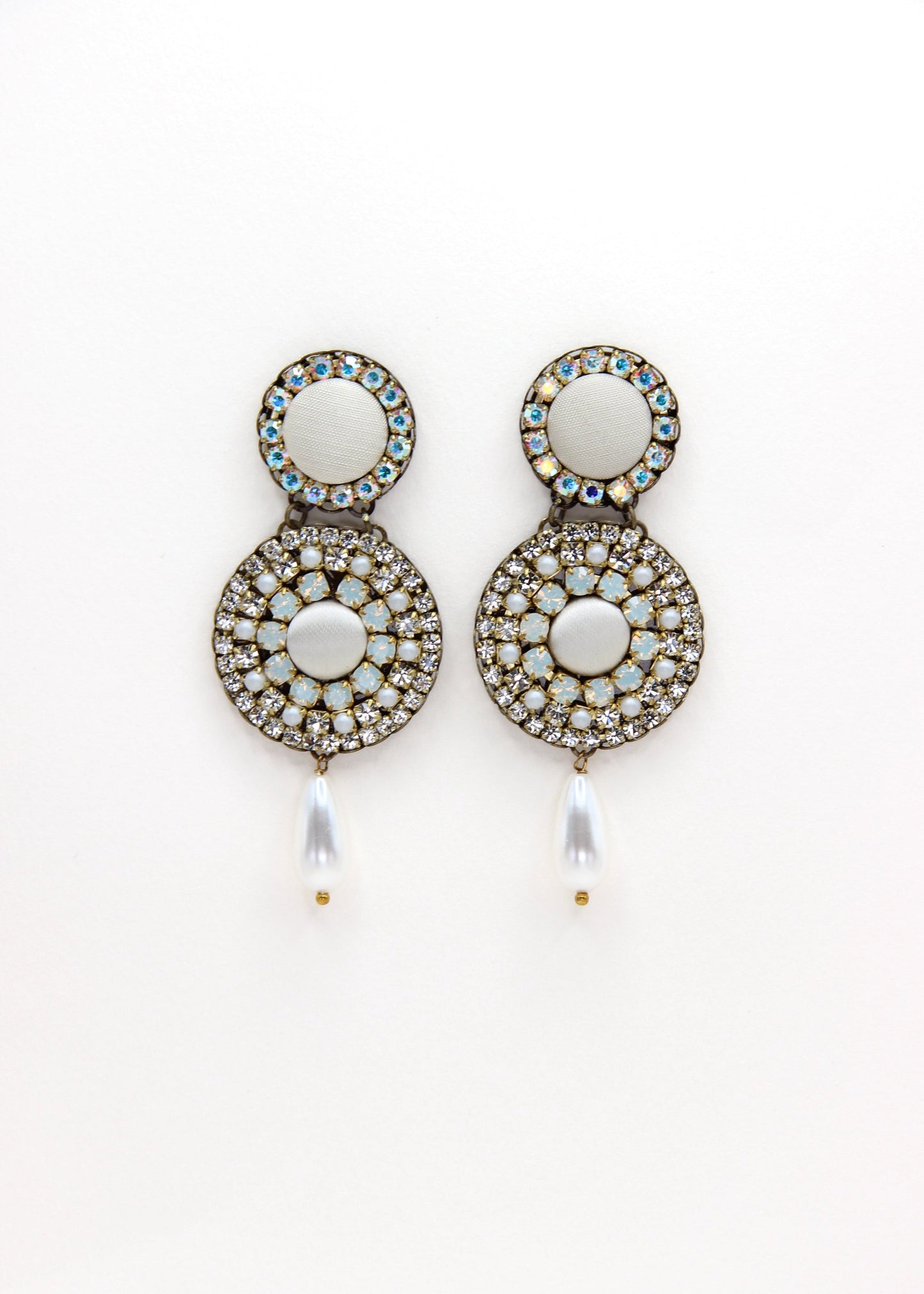 Orecchini artigianali Metropolitan Dubai avorio, con bottoni circolari in tessuto, cristalli iridescenti e pendente a goccia in perla. Nickel free, ideali per cerimonie ed eventi speciali.