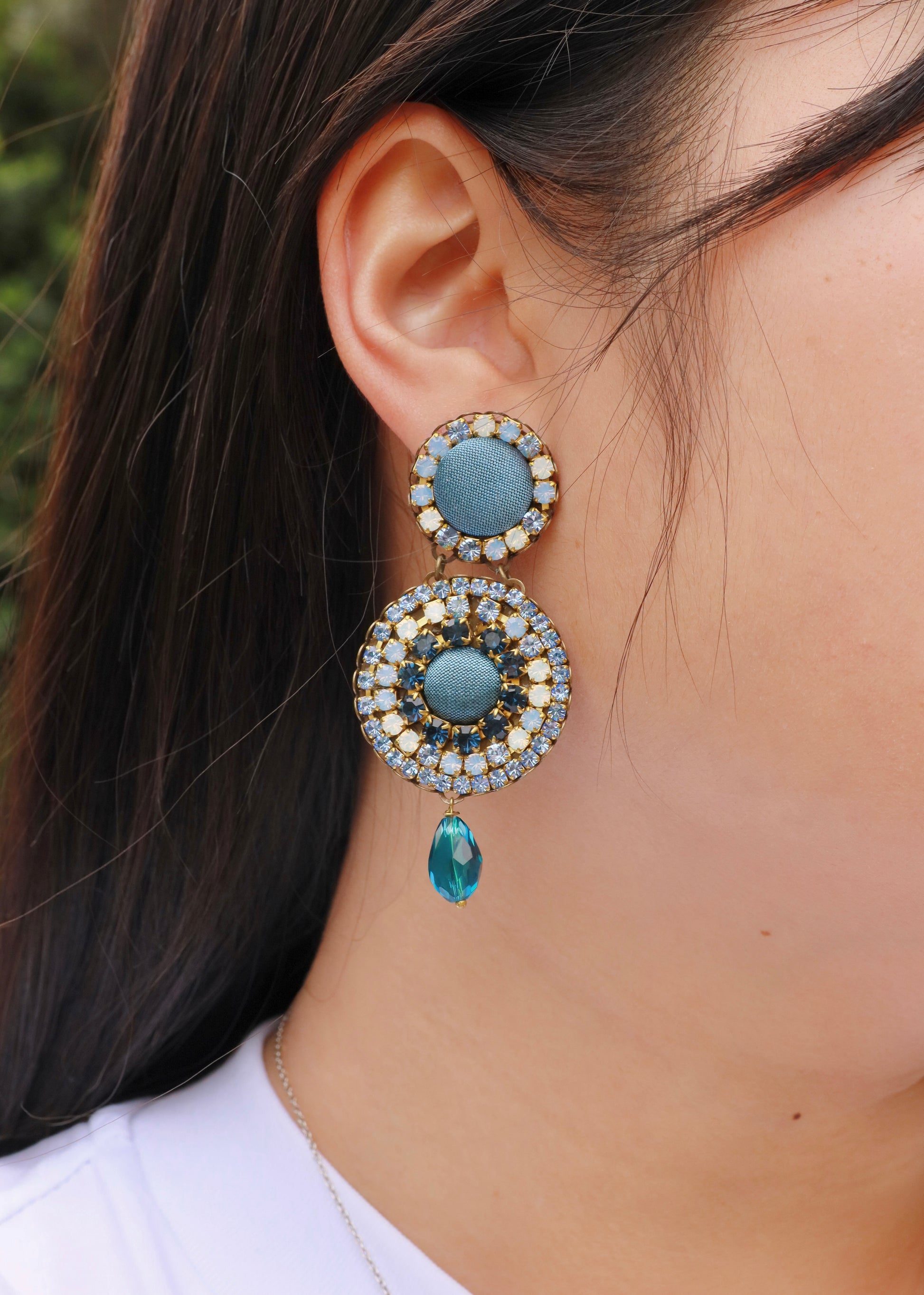 Orecchini artigianali Metropolitan Dubai azzurro, con bottoni circolari in tessuto color carta da zucchero, cristalli in gradiente azzurro e blu e pendente a goccia in cristallo. Nickel free, ideali per cerimonie ed eventi speciali.

