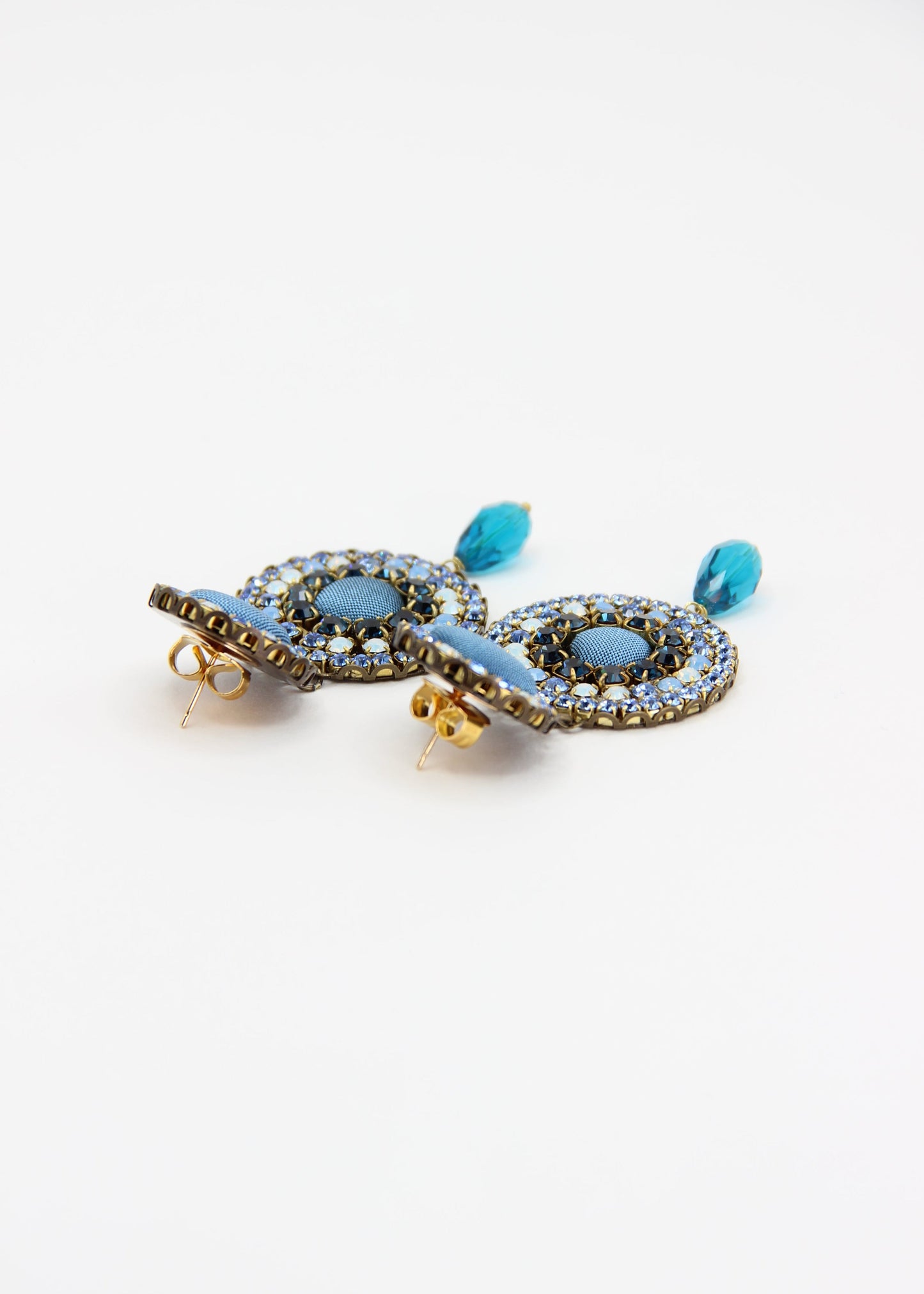 Orecchini artigianali Metropolitan Dubai azzurro, con bottoni circolari in tessuto color carta da zucchero, cristalli in gradiente azzurro e blu e pendente a goccia in cristallo. Nickel free, ideali per cerimonie ed eventi speciali.