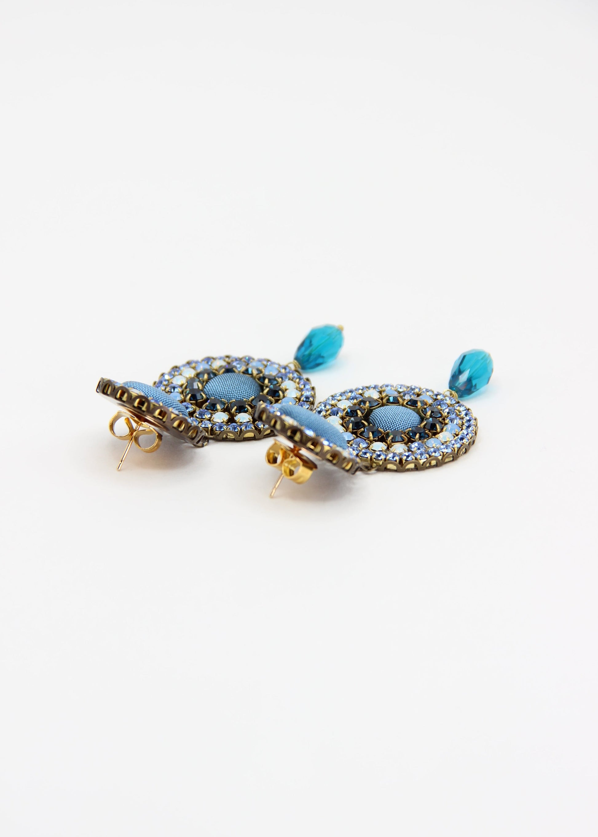 Orecchini artigianali Metropolitan Dubai azzurro, con bottoni circolari in tessuto color carta da zucchero, cristalli in gradiente azzurro e blu e pendente a goccia in cristallo. Nickel free, ideali per cerimonie ed eventi speciali.