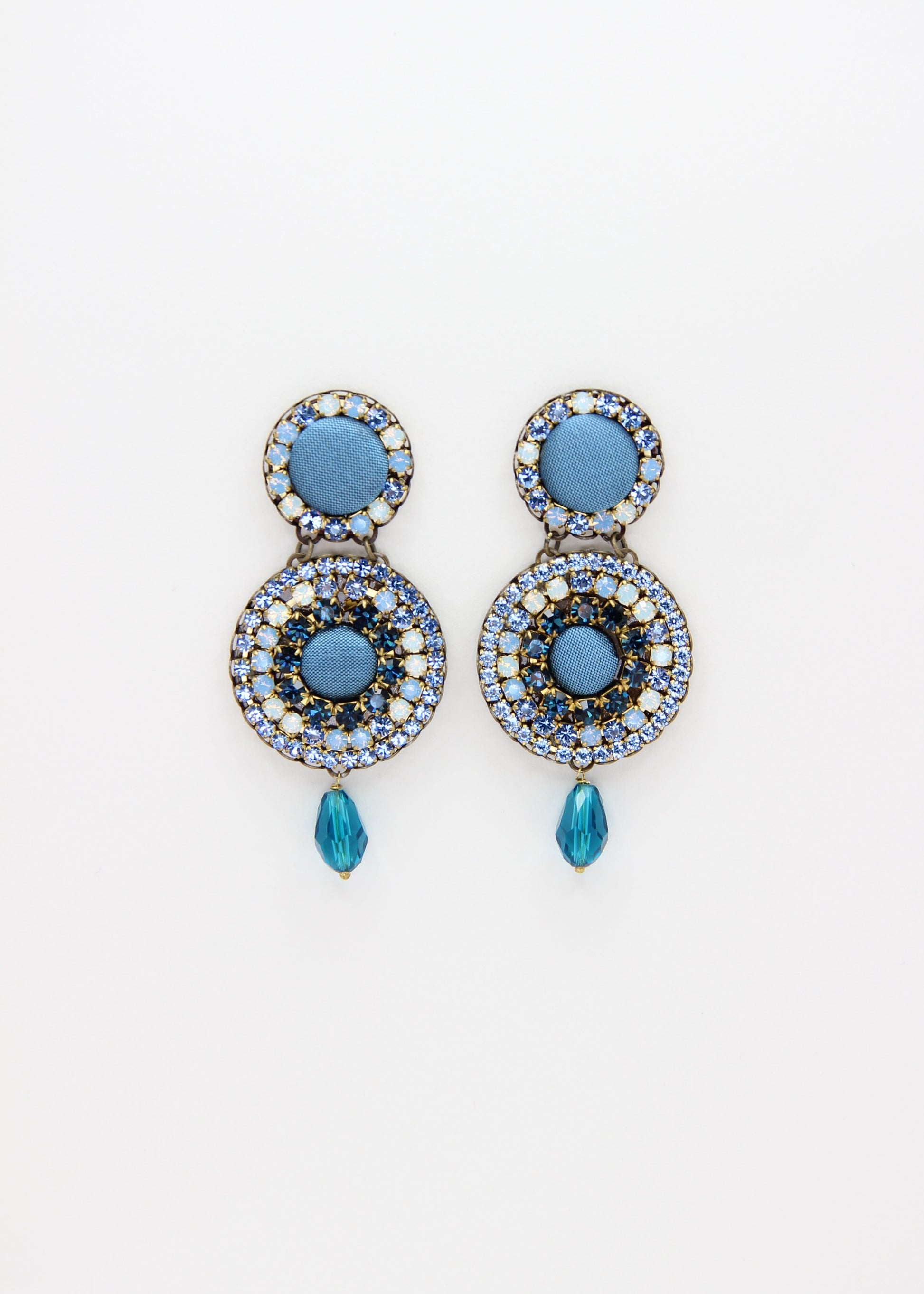 Orecchini artigianali Metropolitan Dubai azzurro, con bottoni circolari in tessuto color carta da zucchero, cristalli in gradiente azzurro e blu e pendente a goccia in cristallo. Nickel free, ideali per cerimonie ed eventi speciali.