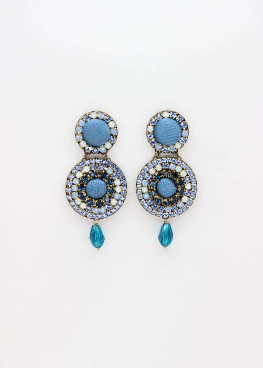 Orecchini artigianali Metropolitan Dubai azzurro, con bottoni circolari in tessuto color carta da zucchero, cristalli in gradiente azzurro e blu e pendente a goccia in cristallo. Nickel free, ideali per cerimonie ed eventi speciali.