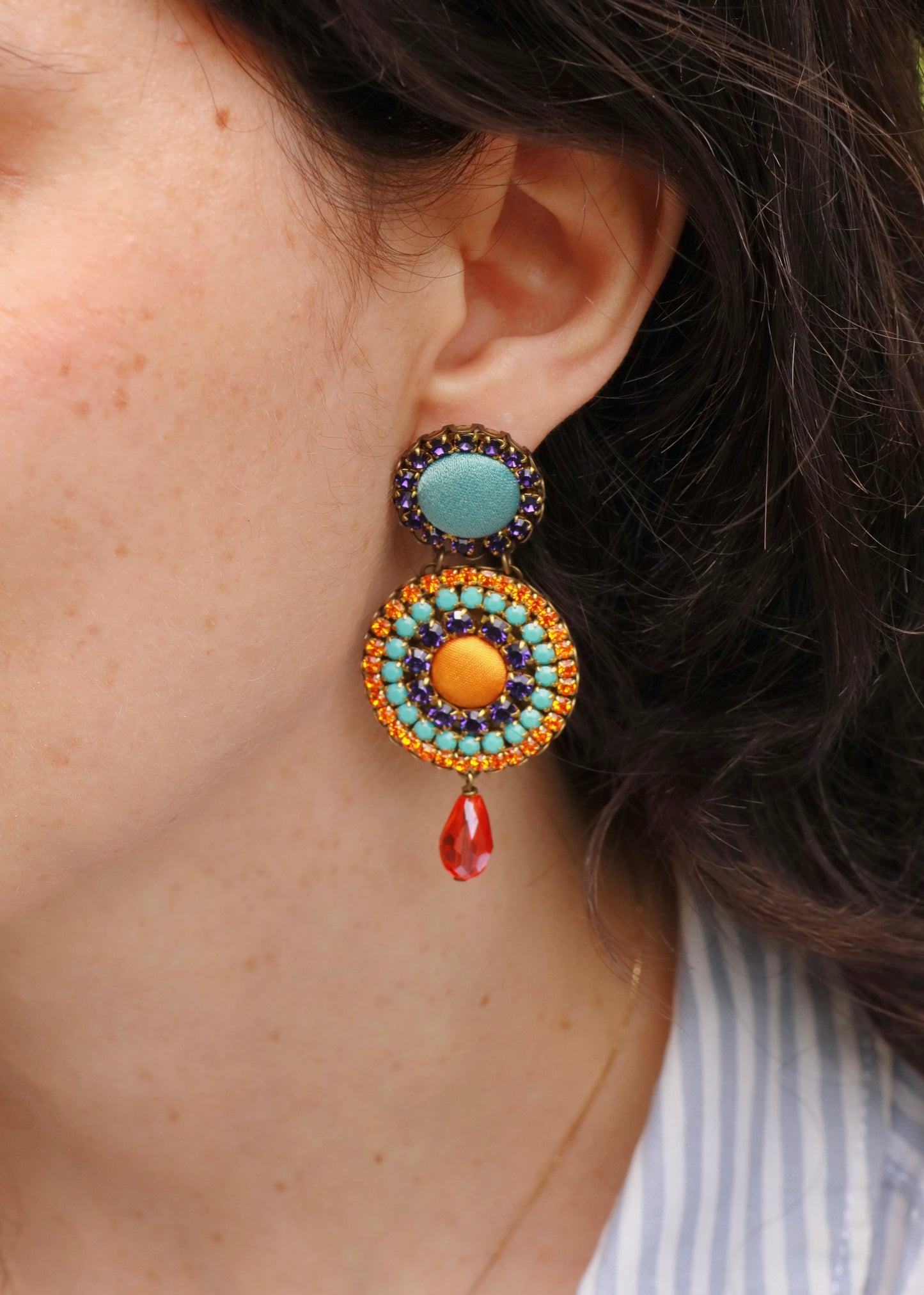Orecchini artigianali Metropolitan Dubai blu e arancione, con bottoni circolari in tessuto azzurro, cristalli in gradiente blu, arancione e azzurro e pendente a goccia in cristallo. Nickel free, ideali per cerimonie ed eventi speciali.