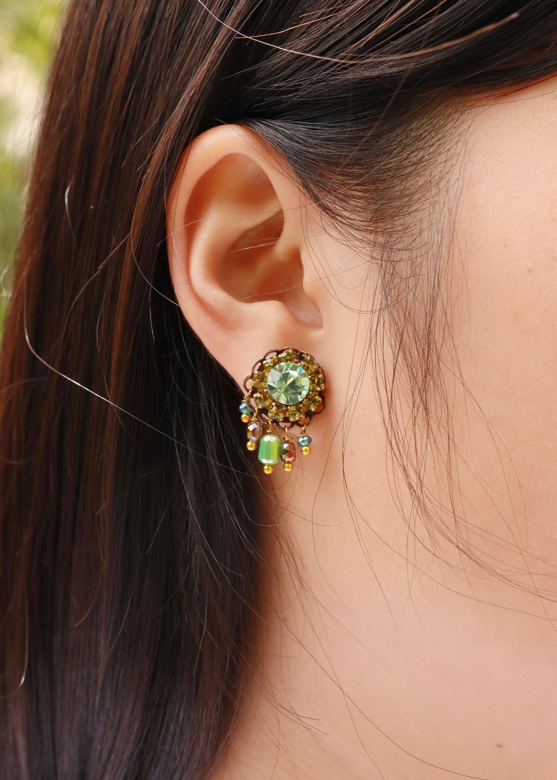 Orecchini artigianali Metropolitan Taormina verde, con cristallo centrale verdeacqua, corona di strass verde oliva e cinque pietre sfaccettate iridescenti a cascata. Nickel free, stile mediterraneo per ogni occasione.