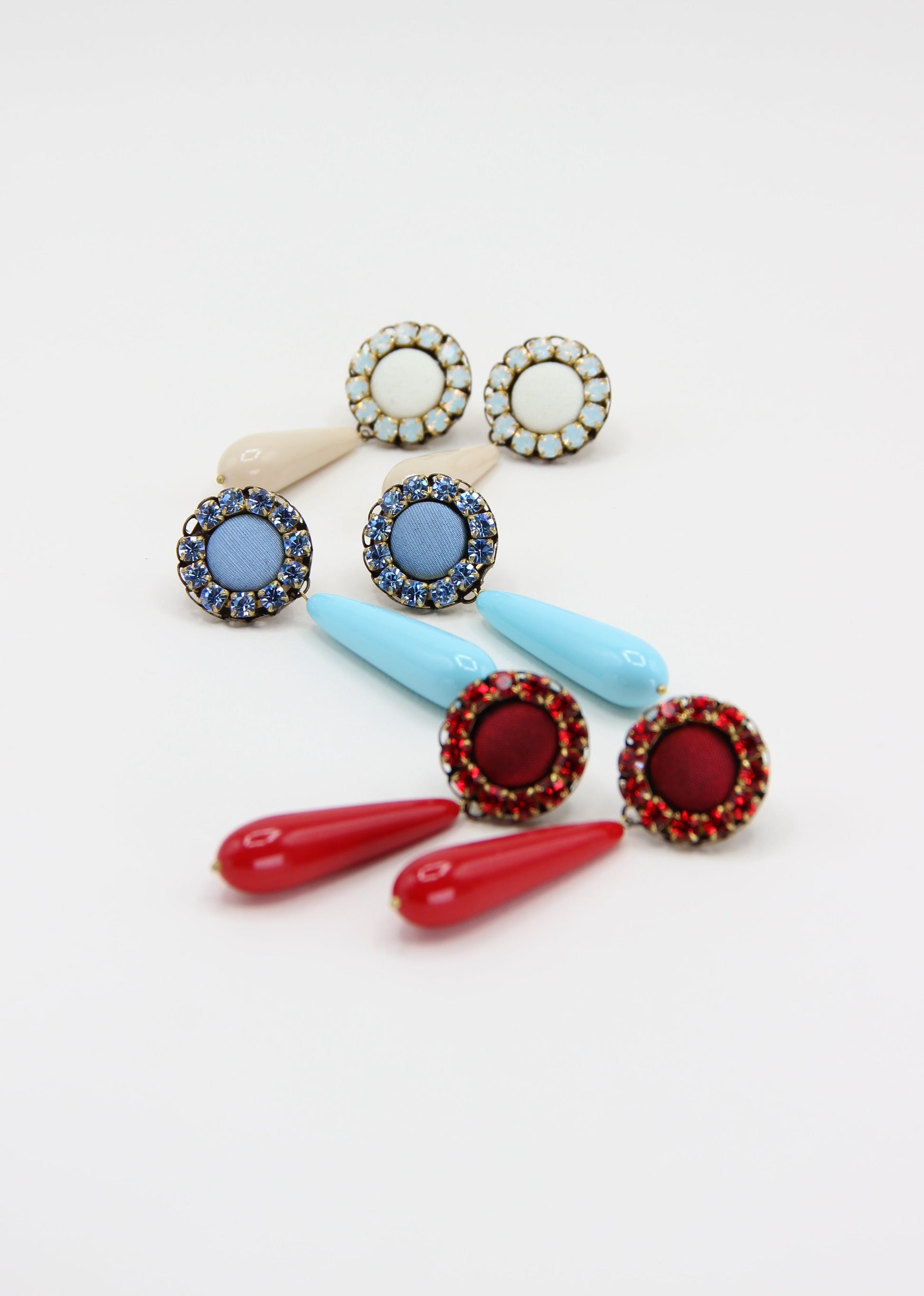 Orecchini artigianali Metropolitan Amalfi azzurro, con bottone circolare in tessuto carta da zucchero, corona di strass azzurri e goccia pendente in resina tono su tono. Nickel free, stile mediterraneo per ogni occasione.