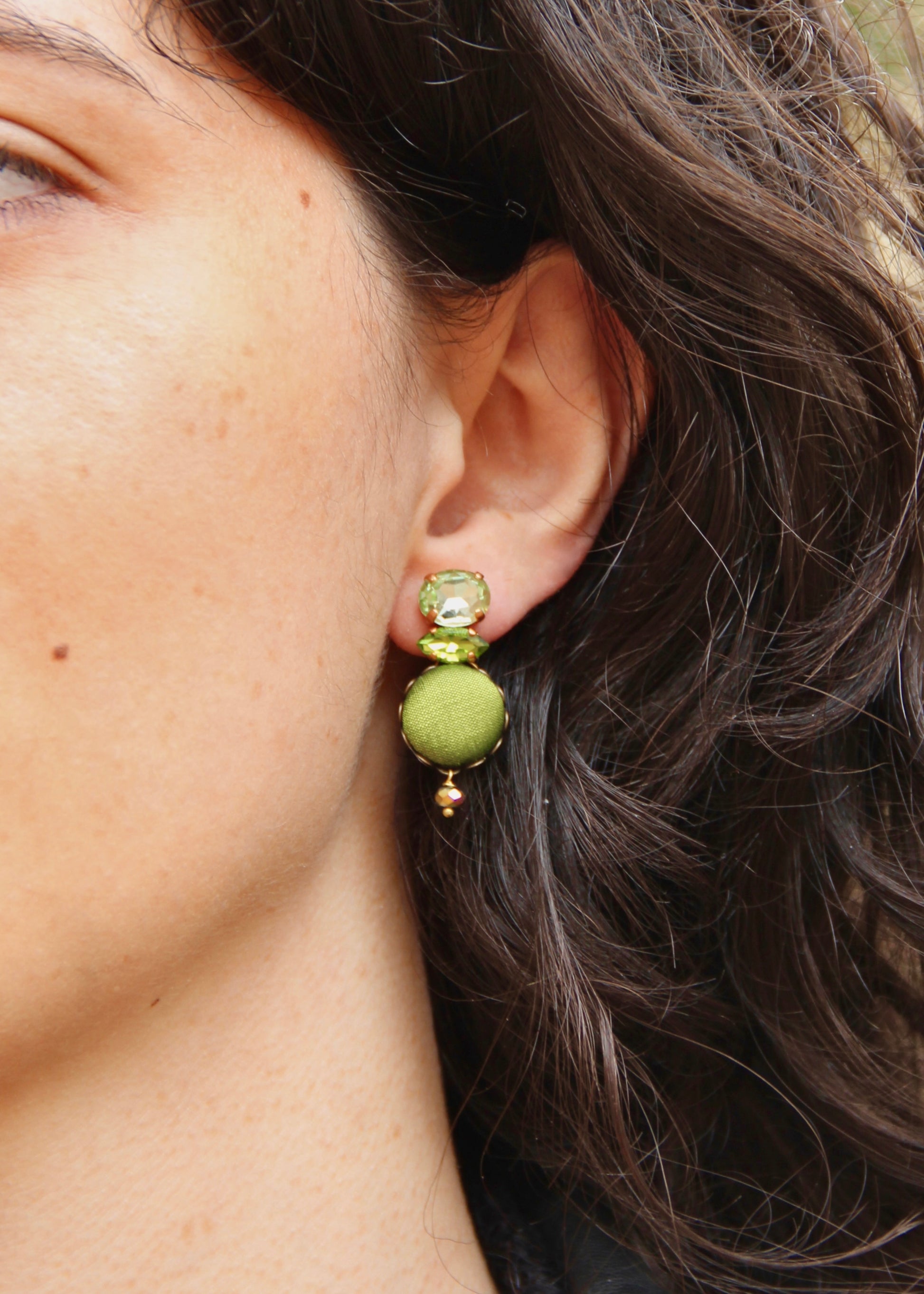 Orecchino artigianale realizzato da Laura Sciunnach Bijoux Metropolitan modello Venezia con bottone in stoffa verde oliva, cristalli tagliati e perlina pendente – gioiello fatto a mano, leggero e personalizzabile, ispirato alla città di Venezia. 